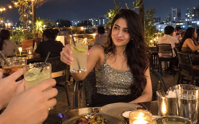 A woman raising a glass at a rooftop restaurant in Bangalore at night