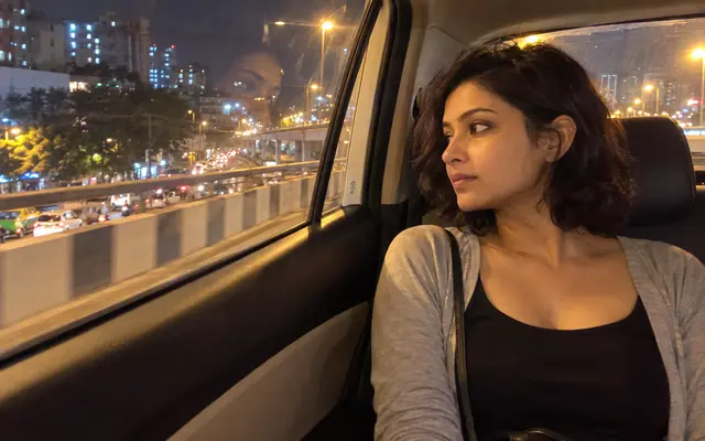 A woman looking out of a white cab on a Bangalore flyover at night